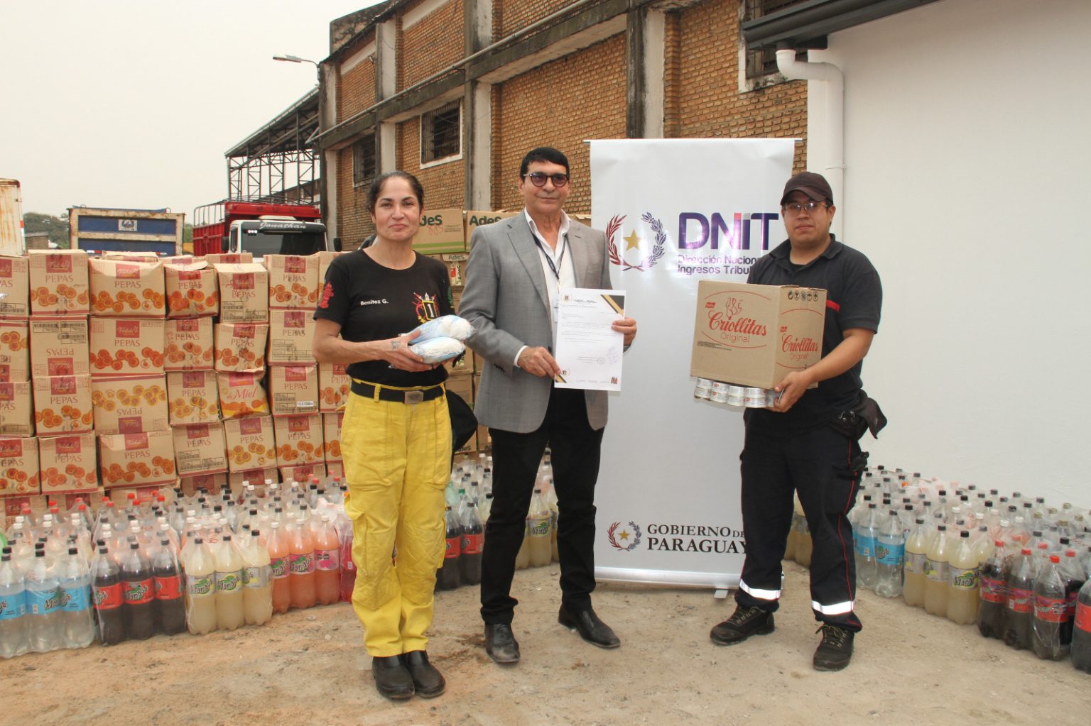 Personas posando junto con alimentos no perecederos donados al Cuerpo de Bomberos.