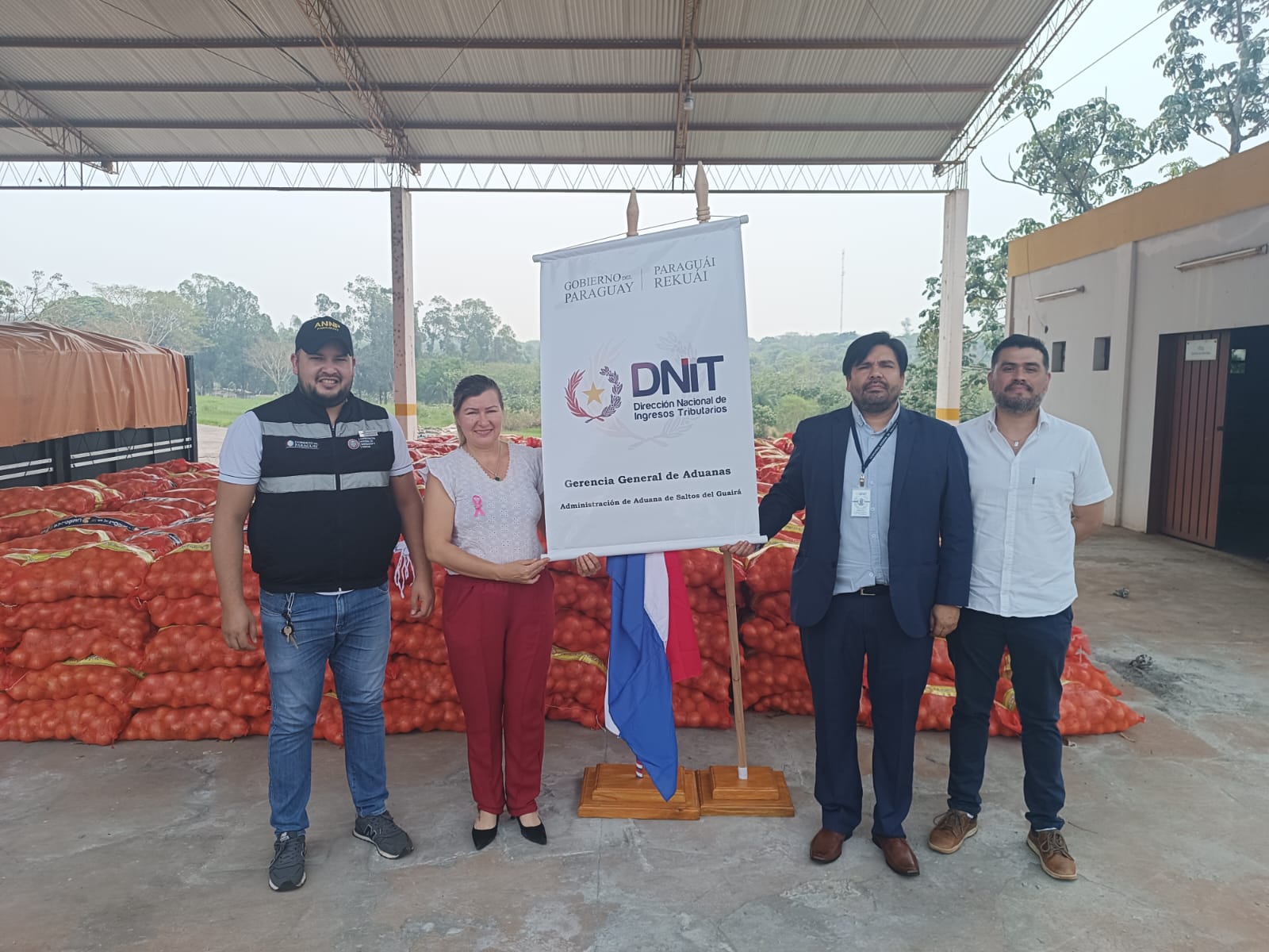 Personas posando junto con las donaciones de tomates.